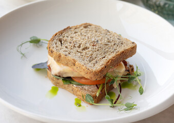 tasty delicious sandwich in plate and lemonade from orange and strawberry.2 bread slices from wholemeal flour with meat,cheese, tomatoes between.microgreen in plate.healthy eating in restaurant.