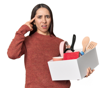 Caucasian young woman holding a box for moving on studio background showing a disappointment gesture with forefinger.