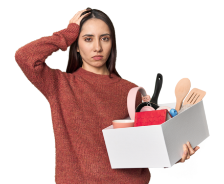 Caucasian young woman holding a box for moving on studio background being shocked, she has remembered important meeting.