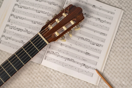 Guitar composition. Image depicting the writing and composition of a guitar sheet music with a sheet music, a guitar neck and a wooden pencil.