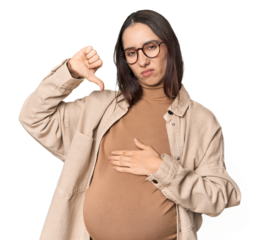 Pregnant young Caucasian woman showcasing maternity on studio background showing thumb down, disappointment concept.