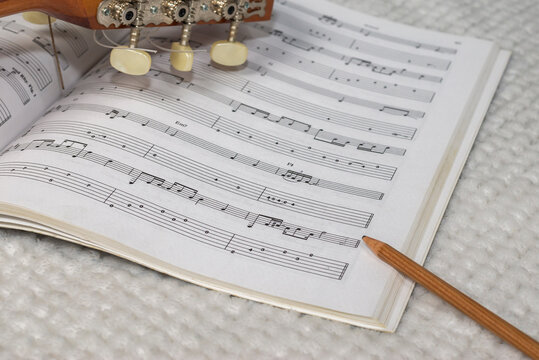 Writing scores. Image depicting the writing and composition of a guitar sheet music with a sheet music, a guitar neck and a wooden pencil.