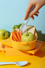 Yellow lunch box with bread, apple and carrot