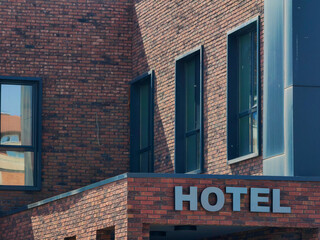 Hotel metal signage, part of building brick wall background . Iron Letters , font style . Windows glass frames.