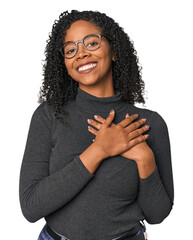 African American woman in studio setting has friendly expression, pressing palm to chest. Love...