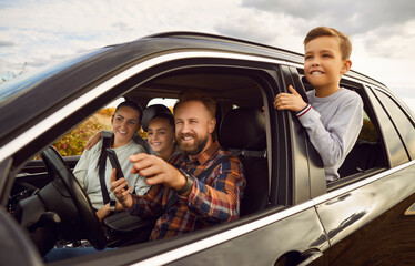 Portrait of happy smiling family of four with kids sitting inside car driving automobile. Father...