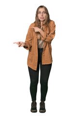 Fototapeta premium Studio portrait of a blonde Caucasian woman shocked pointing with index fingers to a copy space.