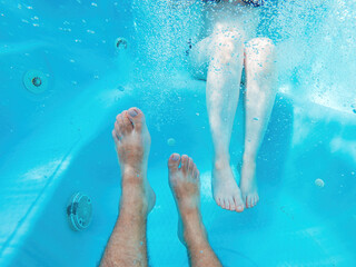 Couple in hot tub, underwater shot of male and female legs in water