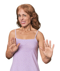 Redhead mid-aged Caucasian woman in studio rejecting someone showing a gesture of disgust.