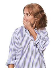 Redhead mid-aged Caucasian woman in studio thoughtful looking to a copy space covering mouth with hand.