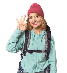 Middle-aged Caucasian woman with hiking gear cheerful and confident showing ok gesture.