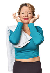 Fototapeta premium Caucasian woman in sportswear with towel covering ears with hands.