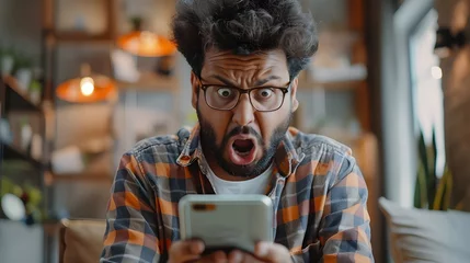 Fotobehang Indian guy staring at smartphone screen with angry face expression, get awful news in notice from bank, bad message, scam, fraud, screams due to short battery life, lagging phone, mobile  Ai Generated © Hamid
