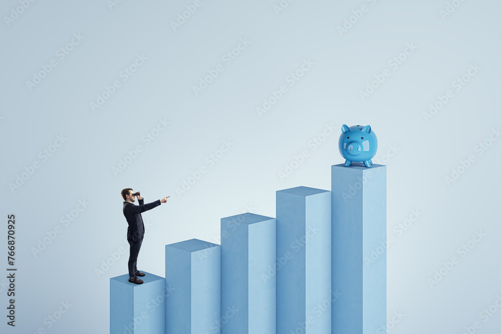 Poster side view of young businessman with binoculars standing on blocks and pointing at piggy bank on blue