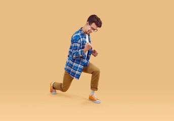 Fototapeta na wymiar Overjoyed man with excited expression waving fists, shouting yeah celebrating his victory and success. Full length of Caucasian man in casual clothes is happy isolated on beige background. Web banner.