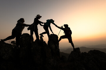 Fototapeta na wymiar Silhouette of hikers climbing up on the mountain,team work and helping concept. Climber success.