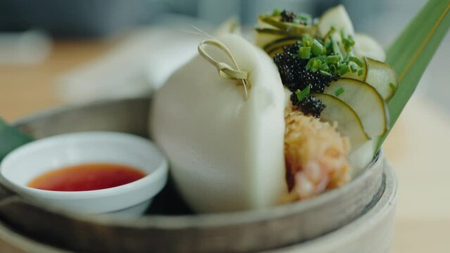 Closeup of japanese gua bao, fresh bun with shrimp and vegetables on plate at cafe. Delicious vegetarian bao bun with shrimp, cucumber and sauce at taiwan restaurant