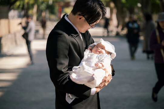 赤ちゃんを抱いてお宮参りの参拝をするお父さん