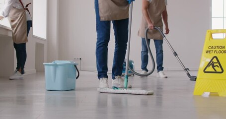 Midsection shot of a cleaners team from a cleaning service staff is cleaning a home or office, mopping, vacuuming the floors, and dusting. Professional service ensures a effective cleaning process.