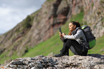 Hiker using phone sitting in the mountain - 766884908