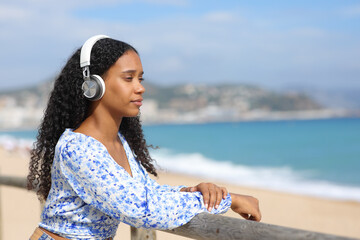 Serious black woman listening audio on the beach