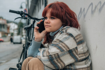 happy plus size teenager with phone and bike on the street