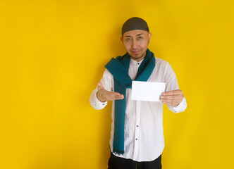 Moslem Asian man holding and giving envelope filled with money. Give donation or Zakat Fitrah as an...