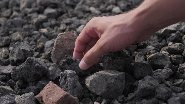Close up shot of a hand picking up a grey stone
