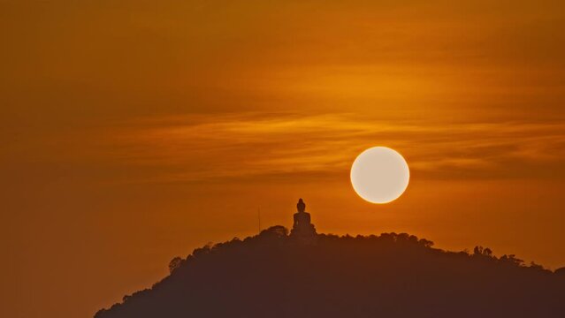 Time Lapse The sun circles behind the Buddha on the mountain as the sun travels from the sky and falls behind the mountain. .The Sky gradually changed color from yellow to orange and red over time...