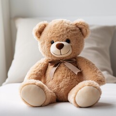 Small plush teddy bear sitting on a white cushion
