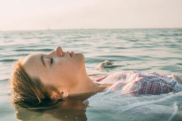 Carefree teenage girl floating on water in sea