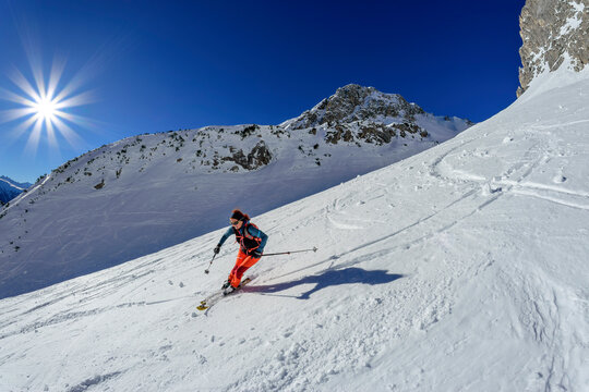 Woman back country skiing downhill on snowcapped Hoelltoerl, Gruenstein, Mieming Range, Tyrol, Austria