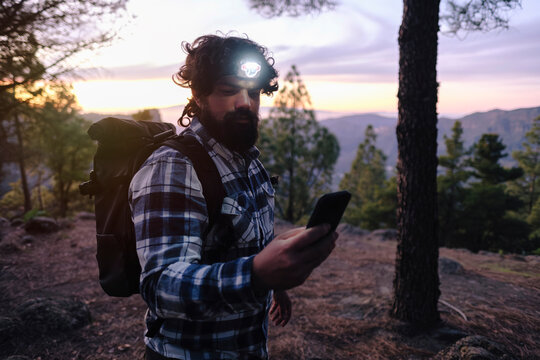 Man wearing headlamp and using smart phone at sunset
