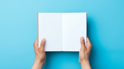hands holding a book over a blue background