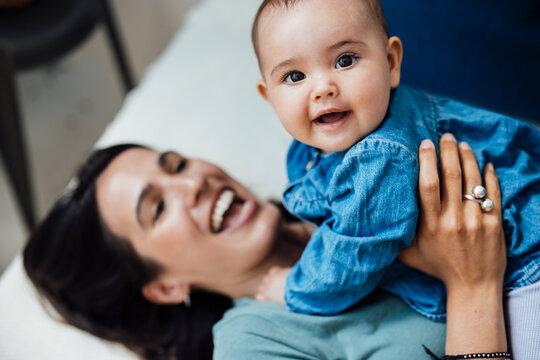 Playful daughter with happy mother on bed