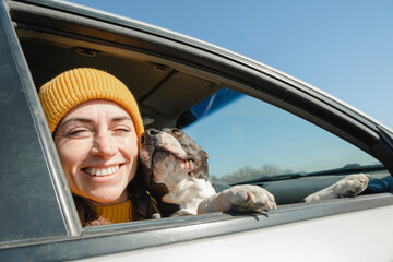 Happy woman sitting with dog in car