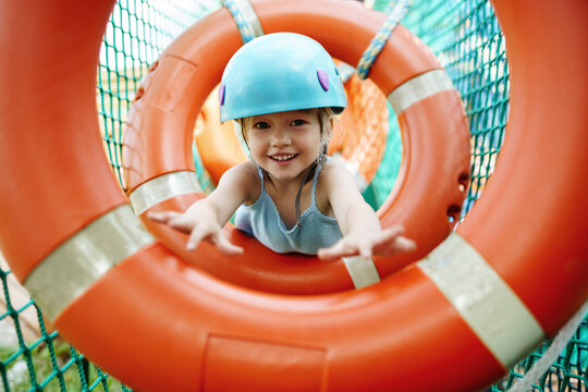 Smiling girl wearing helmet and doing obstacle course at rope park