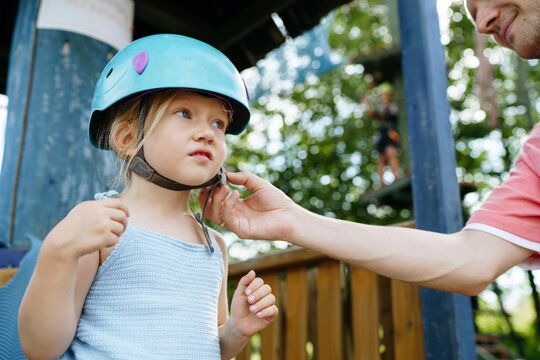 Father fastening helmet of daughter at rope park