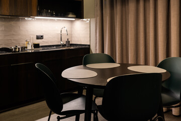 An inviting modern kitchen interior featuring an elegant dining table set with round placemats under warm ambient lightning