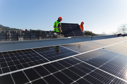 Technicians installing solar panel on sunny day