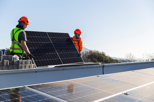 Two engineers installing solar panel on rooftop
