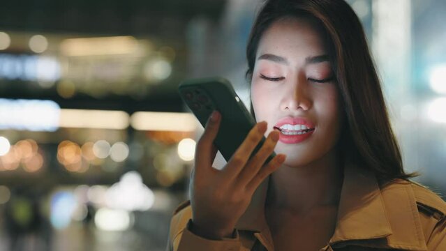 Busy Woman Using Smartphone Voice Recognition Function Standing on Street, Talking to Mobile Assistant. Asian Girl with Cell Phone Voice Recognition, Dictates Thoughts. People and Technology Concept