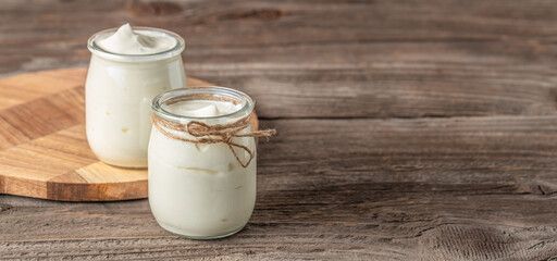 Jars of tasty yogurt on a wooden background. The concept of a lactose-free dairy product, copy space