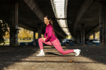 A sportswoman is stretching her leg and preparing for jogging outdoors.