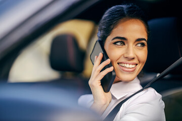 A busy woman is talking on the phone in a car.