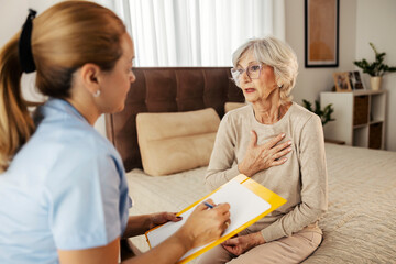 A senior woman with heart problems talking to a doctor at her home visit.