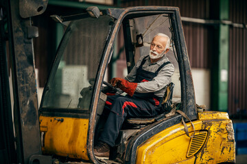 A senior worker is driving forklift.