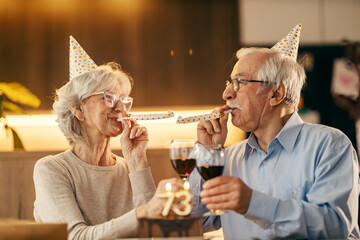 A happy senior couple is celebrating a birthday at home.