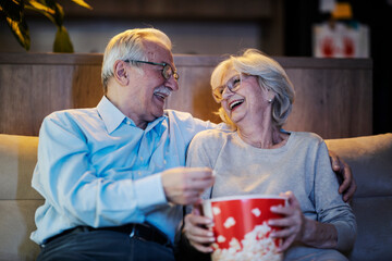 A senior couple having fun at home at movie night. - obrazy, fototapety, plakaty