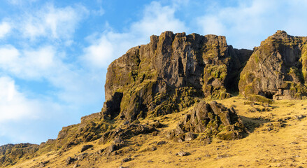 A rocky hillside with a cloudy sky in the background